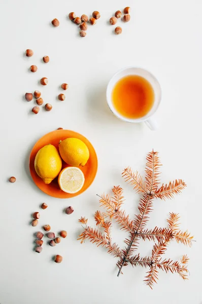 Limones en un plato rodeado de avellanas naranjas en una espalda blanca — Foto de Stock