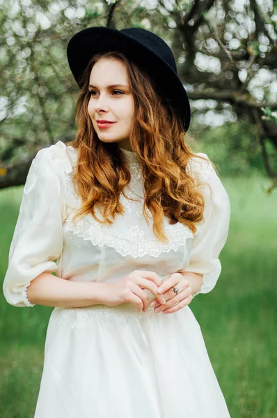 Chica joven en un vestido blanco y sombrero negro en el en el blanco fl — Foto de Stock