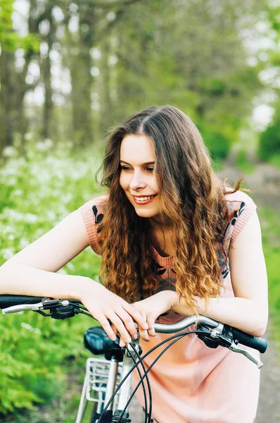 Zarif Bayan hipster Bisiklet şık pembe elbisenin içinde ayakta açık moda portre. Zevk ve having fun Park vsco filtreler ile bahar günü. Uzun kalın dalgalı saçlı güzel kız — Stok fotoğraf