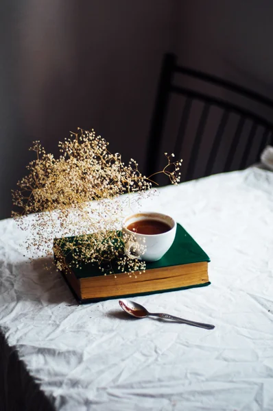 Café caliente fresco en una pila de libros sobre una mesa cubierta con un wh — Foto de Stock