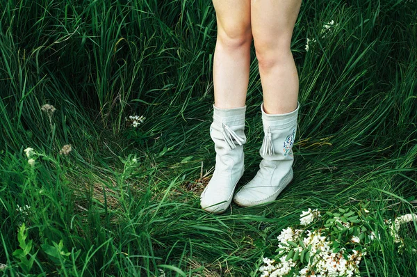 Kvinna ben i vita stövlar på grönt gräs. Kvinnliga fötter i skor — Stockfoto