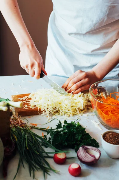 Woman on kitchen cuts vegetables for salad. Dieting and detox dr