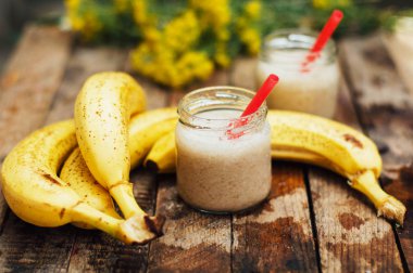Meyve Smoothies. muz smoothies süt ile. Ahşap bir masa üzerinde Muz Smoothie. Sağlıklı Kahvaltı: muz smoothie yulaf ezmesi ile. Muz smoothie cam ahşap zemin üzerine taze meyve ile
