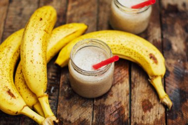 Meyve Smoothies. muz smoothies süt ile. Ahşap bir masa üzerinde Muz Smoothie. Sağlıklı Kahvaltı: muz smoothie yulaf ezmesi ile. Muz smoothie cam ahşap zemin üzerine taze meyve ile