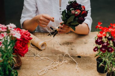 Bir tablo rustik, Bahçe işi bahçıvan. Bahçede çalışan, bir kadın bakımları flowerscarnations el ile kapatın. Kadının elleri. Çiçekli Bahçe aletleri.