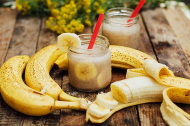 Meyve Smoothies. muz smoothies süt ile. Ahşap bir masa üzerinde Muz Smoothie. Sağlıklı Kahvaltı: muz smoothie yulaf ezmesi ile. Muz smoothie cam ahşap zemin üzerine taze meyve ile