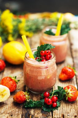 muz ve çilek güler yüzlü. Mutfak masasında malzemelerle bardaklarda iki soğuk çilek muz Smoothies. Çilek Muz Smoothie taze malzemelerle hazırlanan. Taze çilek güler yüzlü