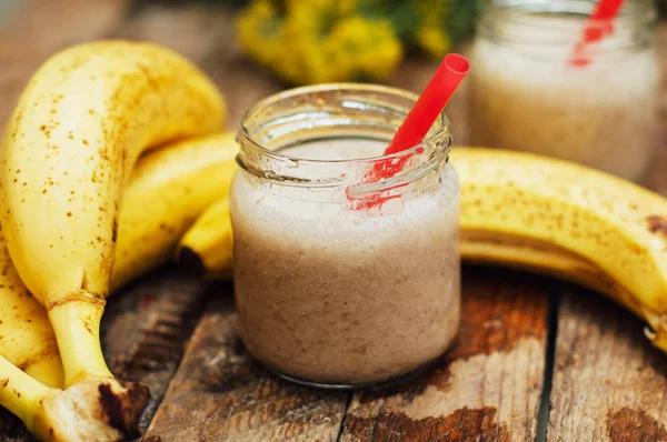 Frucht-Smoothies. Bananen-Smoothies mit Milch. Bananen-Smoothie auf einem Holztisch. gesundes Frühstück: Bananen-Smoothie mit Haferflocken. Bananen-Smoothie im Glas mit frischen Früchten auf Holzgrund — Stockfoto