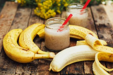 Meyve Smoothies. muz smoothies süt ile. Ahşap bir masa üzerinde Muz Smoothie. Sağlıklı Kahvaltı: muz smoothie yulaf ezmesi ile. Muz smoothie cam ahşap zemin üzerine taze meyve ile