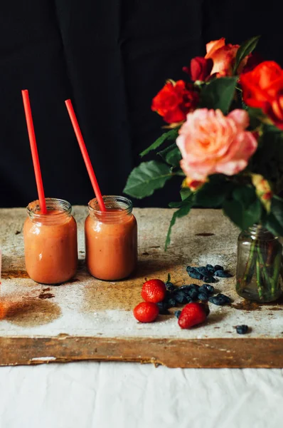 Hands makes strawberry smoothies in wooden table . Fresh strawbe