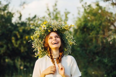 güneşli çayırda çiçek çelenk güzel kız. Kır çiçekleri bir çelenk giyen genç güzel kadın portresi. Genç pagan Slav kız yaz ortası üzerinde töreni yapmak.