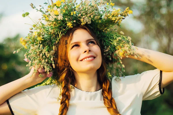 Bella ragazza nella ghirlanda di fiori nel prato nella giornata di sole. Ritratto di Giovane bella donna che indossa una corona di fiori selvatici. Giovane pagana ragazza slava cerimonia di condotta in mezza estate . — Foto Stock