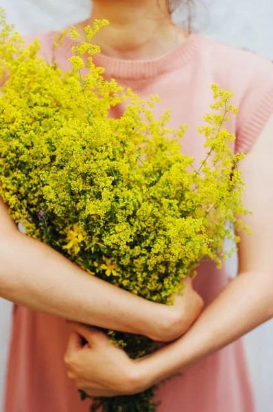 young woman in a rosy dress holding a bunch of colorful picked w