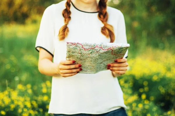 Mujer en el campo. Joven mujer caucásica senderismo con mochila mirando el mapa. Primer plano de las manos de la mujer sosteniendo un mapa . — Foto de Stock