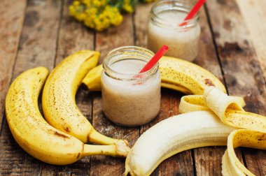 Meyve Smoothies. muz smoothies süt ile. Ahşap bir masa üzerinde Muz Smoothie. Sağlıklı Kahvaltı: muz smoothie yulaf ezmesi ile. Muz smoothie cam ahşap zemin üzerine taze meyve ile