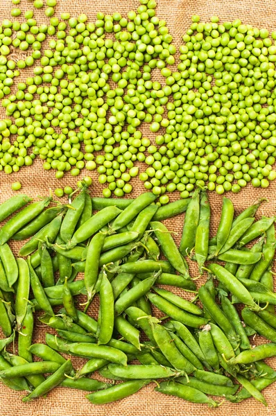 Frozen peas  on a table. Pea pods on green background — Stock Photo, Image