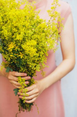 young woman in a rosy dress holding a bunch of colorful picked w