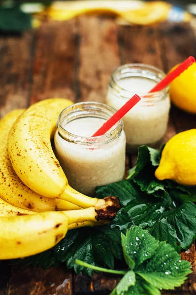 Batidos de frutas. batidos de plátano con leche. Batido de plátano en una mesa de madera. Desayuno saludable: batido de plátano con avena. Batido de plátano en vidrio con frutas frescas sobre fondo de madera —  Fotos de Stock