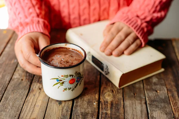 Woman holding cup of hot chocolate. Hot Chocolate in wooden tabl