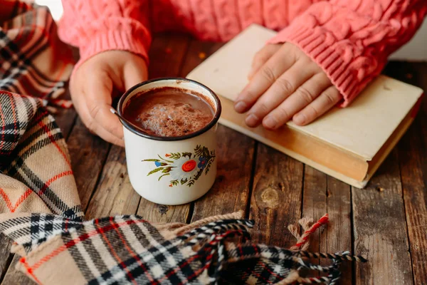 Mulher segurando xícara de chocolate quente. Chocolate quente em tabl de madeira — Fotografia de Stock