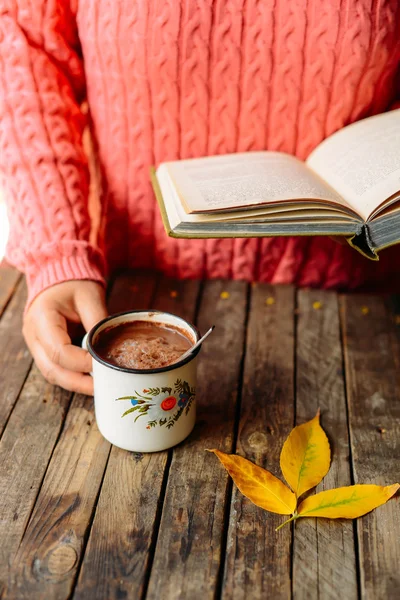 Mujer sosteniendo una taza de chocolate caliente. Chocolate caliente en tabla de madera — Foto de Stock