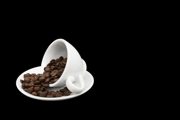 Beyaz kahve fincanı dökülen kahve çekirdekleri ile