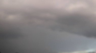 Koyu gri ve ince pembe bulutların bulanık katmanlarını içeren bulutlu bir gökyüzünün soyut uzun pozlama fotoğrafı metin veya tasarım elementleri için dengesiz bir atmosferik doku ve arkaplan oluşturur.