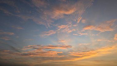 Dramatik bir gökyüzü ufukta parlak turuncu, sarı renkler barındırır. Kalıplı bulutlar daha serin mavi bölgelere yükselir, katmanlı, canlı, ruhani atmosfer manzarası, barışçıl yakın çekim.