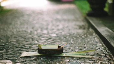 Geleneksel Balili Canang Sari adağı, Endonezya, Bali 'de günlük bağlılığı simgeleyen hafif tütsü dumanıyla sabah taş bir patikaya yerleştirildi..