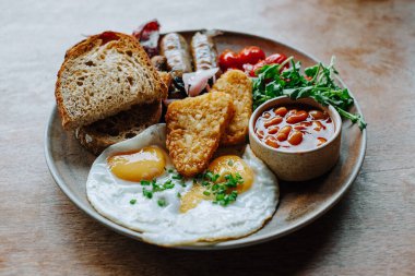 Geleneksel İngiliz kahvaltısı yumurtalar, sosisler ve kırsal ahşap bir masada fasulyeler otantik yerel mutfağı ve seyahat yemek deneyimlerini gözler önüne seriyor.