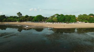 Geleneksel deniz manzarası ve yerel balıkçı teknelerinin yer aldığı, otantik Endonezya kıyı kültürü ve seyahat merkezini temsil eden Sanur Sahili, Bali 'nin insansız hava aracı görüntüsü