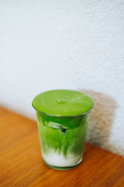 Sağlıklı kafe kültürünü, sağlıklı yaşam tarzını ve otantik Asya mutfağı deneyimlerini temsil eden, tahta bir masanın üzerindeki bir bardakta buzlu kibrit sütlü latte..