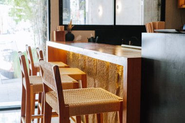 Ahşap tabureleri ve tezgahı olan minimalist bir kafenin iç manzarası, konukseverlik, küçük işletmeler ve seyahat kavramları için bir iç yapı tabağı görevi görüyor..