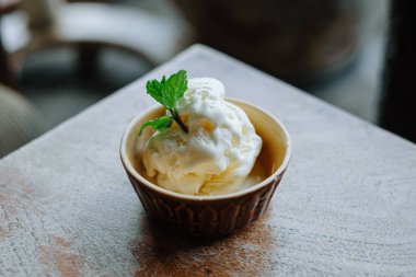 Naneli ve vanilyalı dondurma, yerel kafe kültürünü, yaz tatlısını ve otantik yemek deneyimlerini temsil eden ahşap bir masada seramik bir kasede servis edilir..