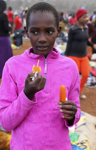 Portrait of  African teenage girl eating a popsicle at Karatu Iraqw Market, Tanzania