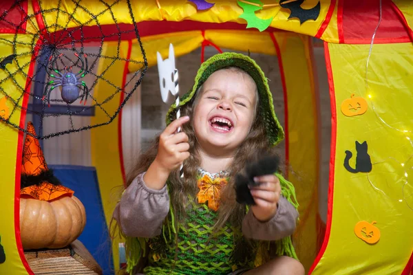 森の妖精のような服を着た小さなかわいい女の子は コウモリや幽霊 クモとクモの巣 オレンジのカボチャでハロウィーンのために飾られた子供のテントに座っています — ストック写真