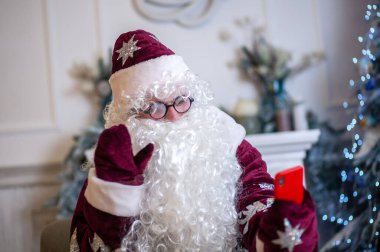 Noel Baba 'nın yakın plan portresi, gözlüklü, kocaman kıvırcık sakallı, Noel ve Yeni Yıl için parlak kırmızı kostümlü kış şenliği karakteri..