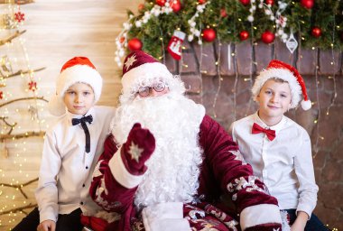 Noel Baba 'nın iki çocukla portresi, Noel Baba şapkalı kardeşler, Noel ve yeni yıl, çocuklar evde kaldı..