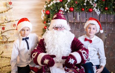 Noel Baba 'nın iki çocukla portresi, Noel Baba şapkalı kardeşler, Noel ve yeni yıl, çocuklar evde kaldı..