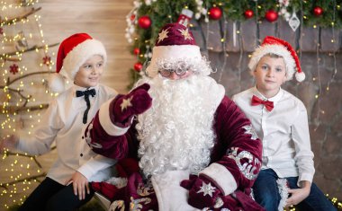 Noel Baba 'nın iki çocukla portresi, Noel Baba şapkalı kardeşler, Noel ve yeni yıl, çocuklar evde kaldı..