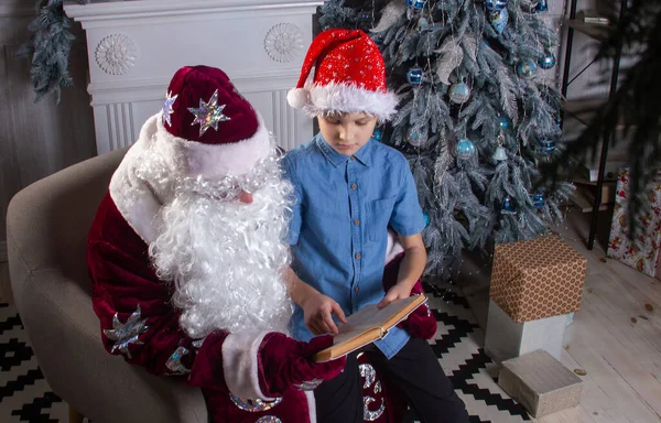 Papai Noel Menino Bonito Estão Sentados Árvore Natal Lendo Livro — Fotografia de Stock