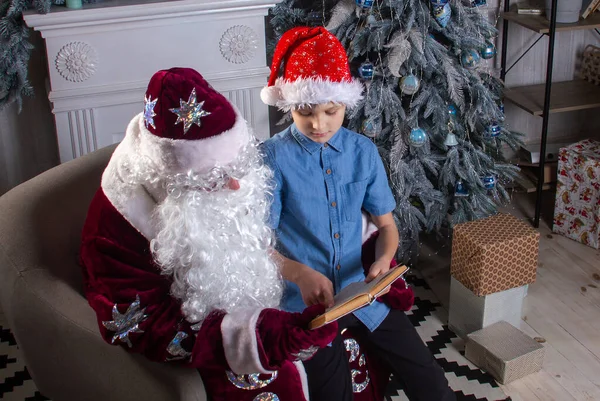 Papai Noel Menino Bonito Estão Sentados Árvore Natal Lendo Livro — Fotografia de Stock