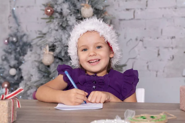 Симпатичная Маленькая Девочка Пишет Новогоднее Письмо Санта Клаусу Ребенок Сидит — стоковое фото