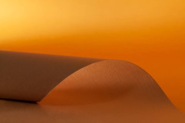 Turuncu ve kahverengi kağıt dalgalı bir çizgi, güzel yumuşak bir ışık ve kağıt üzerinde gölge, tasarımcılar için soyut bir arkaplan tarafından eğrilir..