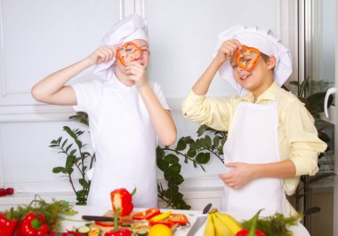 Aşçı gibi giyinmiş iki yakışıklı Avrupalı çocuk, mutfakta oynuyorlar.
