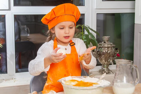 Маленькая Симпатичная Девочка Оранжевом Костюме Шеф Повара Разбивает Сырое Яйцо — стоковое фото