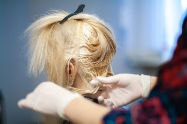 Saç boyama açık tonda, genç Avrupalı bir kadın saçını kuaförde boyuyor, kuaförde çalışıyor, güzellik salonunda çalışıyor..