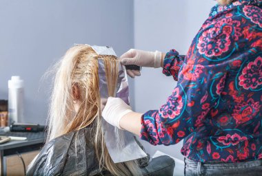 Saç boyama açık tonda, genç Avrupalı bir kadın saçını kuaförde boyuyor, kuaförde çalışıyor, güzellik salonunda çalışıyor..