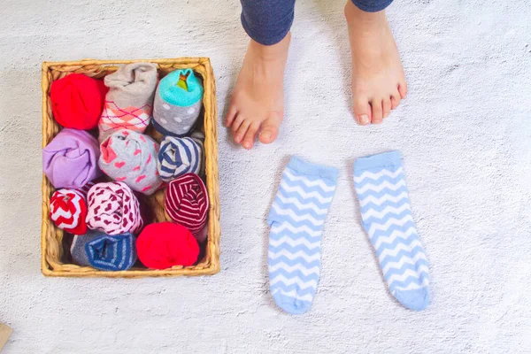 Barfüßiges Kind Und Ein Großer Korb Zusammengerollter Socken — Stockfoto