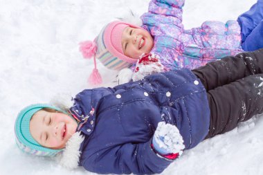 Kış tulumlu iki küçük kız kışın karda oynuyorlar. Keskinlik, özel bulanıklık..